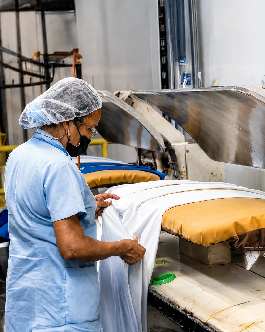 Cadillac laundry operator pressing fabric on industrial equipment