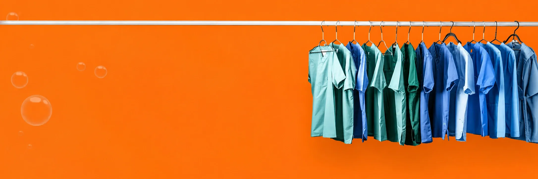 Scrubs hanging on a rack against a vivid orange background